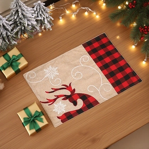 Set de table de Noël avec motif à carreaux et renne brodé sur une table en bois naturel