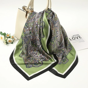 Green paisley silk scarf draped elegantly on a handbag with satin texture details