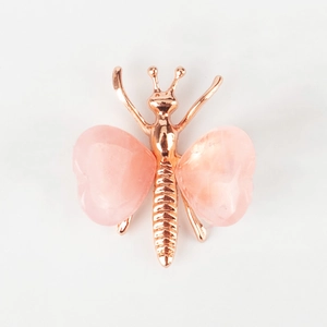 Macro detail of rose gold butterfly ornament with smooth heart-shaped pink crystal wings