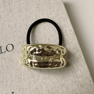 Macro detail of elastic hair tie with vintage gold hammered metal texture accent