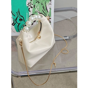 Detail of white soft-touch handbag featuring a pearl handle and heart-shaped zipper pull