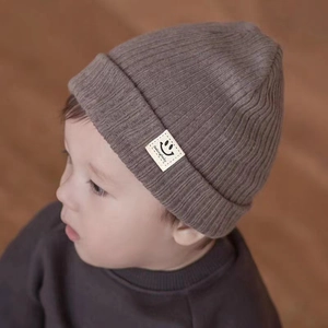Knitted baby beanie with smiling face patch in warm coffee brown ribbed fabric