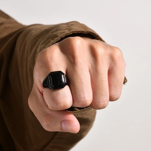 Close-up of a polished black square ring for men shown on a model's clenched fist