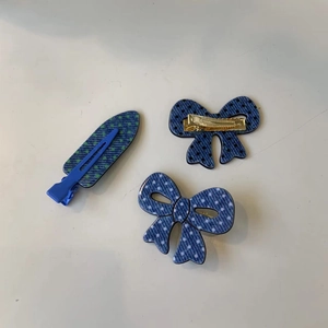 Close-up of three blue denim polka dot bow hair clips with durable metal springs