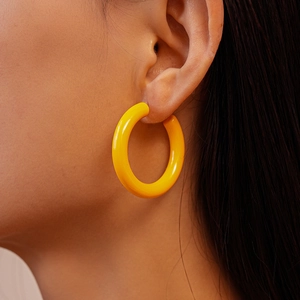 Gros plan de boucles d'oreilles créoles épaisses en résine jaune poli pour femme