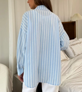 Détail d'une chemise oversize à rayures verticales bleues et blanches montrant le drapé