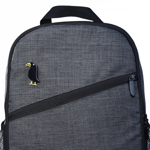 Fashionable black acrylic crow brooch pinned on grey nylon backpack with modern design