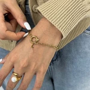 Detail of a gold sailor clasp bracelet with letter L pendant and a pearl ring