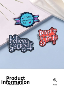 Close-up of three motivational enamel pins with sayings on white satin background