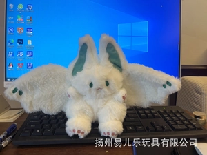 Detailed close-up of a white plush rabbit with wings and green toe pads on a desk