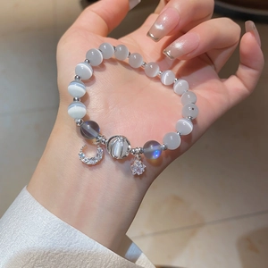 Macro shot of grey cat eye beads bracelet with crescent moon and star charms