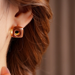 Close-up of a French vintage square brown oil-drip earring with gold trim on ear