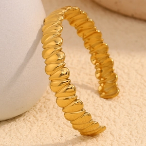 Close-up of a 18K gold plated croissant style spiral cuff bracelet on a minimalist background