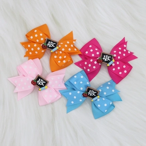 Close-up of four polka dot bow hair clips with back-to-school ABC and apple accents
