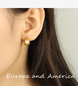 Detail of irregular liquid gold earrings featuring a central white pearl on a model's ear