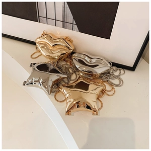Macro shot of stylish gold and silver metallic star and lip shaped mini handbags with chains