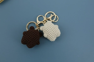 Close-up of handmade crochet bear keychains in brown and beige with gold metal rings
