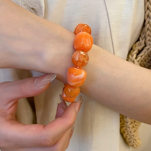 Gros plan du bracelet en perles acryliques orange avec texture marbrée style d'été