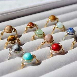 Macro shot of assorted handmade wire-wrapped rings with multi-color stone beads on a tray