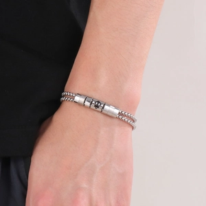 Detail of silver double-chain steel bracelet with engraved anchor cylindrical bead