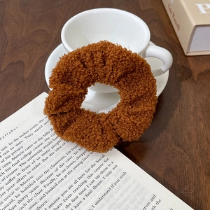 Brown teddy fleece scrunchie for hair with soft texture styled on a white cup and book