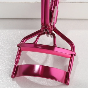 Macro detail of pink stainless steel eyelash curler with soft silicone pad and precision hinge