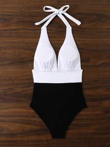 Costume intero bicolore a fascia con top bianco e fondo nero su legno scuro