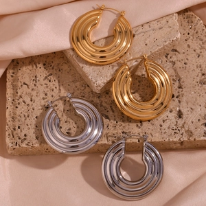 Detailed view of 18K gold and silver hoop earrings with textured wavy patterns on stone
