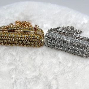 Detail view of mini lipstick crossbody bags in gold and silver with sparkling rhinestones
