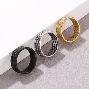 Three men's titanium rings in black, silver, and gold with textured grid patterns