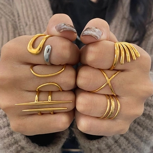 Detail of stacked irregular geometric rings in gold and silver finish on hands