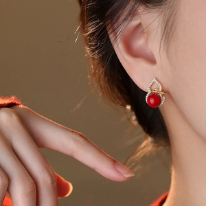 Gourd earrings with red agate bead and gold bow tie on a model in close-up shot