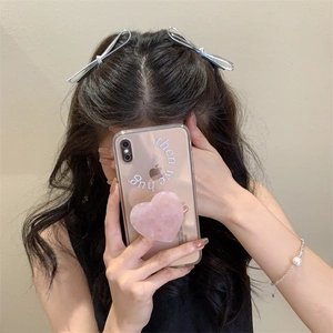 Detail view of silver bow hair clips and a pink heart phone socket on a person