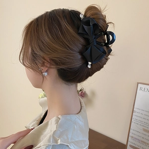 Detail of elegant black satin ribbon bow hair claw clip with rhinestones worn by a model
