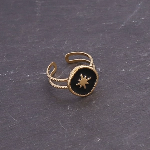Detail of adjustable gold ring featuring a black enamel starburst design and texture