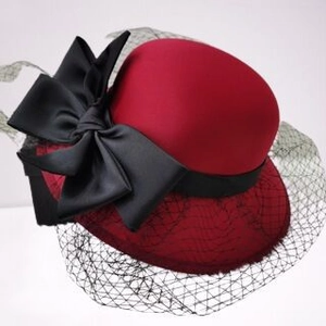 Close-up of elegant red hat with black mesh veil and satin bow for formal parties