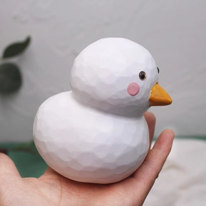 Miniature white wooden duck figurine with hand-carved texture shown held in hand