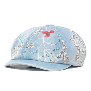 Detail of light blue denim beret featuring vintage red and white floral patterns