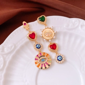 Close-up of asymmetric vintage zircon earrings featuring Hamsa Hand and Evil Eye elements