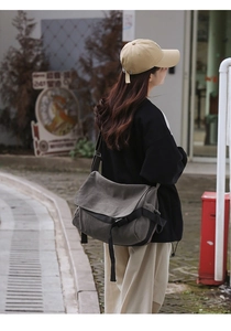 Detailed view of gray canvas messenger bag with black buckle and adjustable strap
