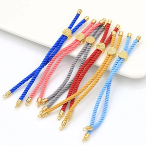Close-up of adjustable woven cord bracelets with engraved golden sliders in various colors