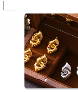Close-up of golden and silver twisted knot earrings on a wooden jewelry display case