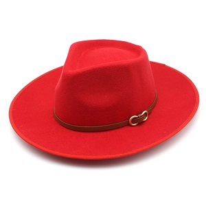Detail of red wool fedora hat featuring a brown leather band and golden horsebit buckle