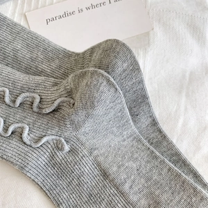 Detailed macro view of gray ribbed knit socks featuring delicate ruffled lettuce edges