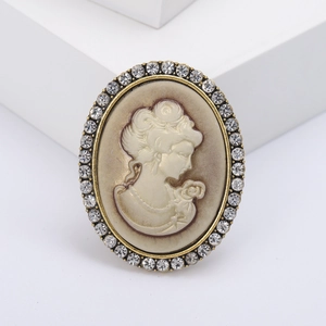 Vintage bronze lady relief brooch with sparkling rhinestones on a white display stand