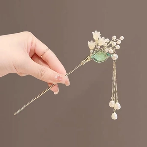 Detail of a golden lily of the valley hair pin with white flowers and elegant tassels