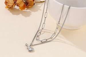 Detail shot of silver double-layered necklace featuring a sleek electric guitar pendant