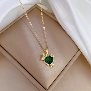 Detail of heart-shaped green emerald pendant with gold chain on silk background