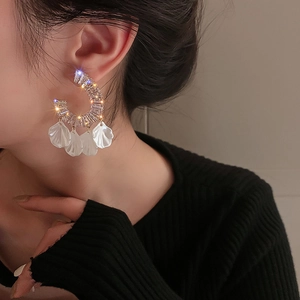 Eleganti orecchini a cerchio a C con zirconi e nappe a petalo bianco su modella