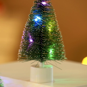 Close-up of mini LED Christmas tree with colorful lights and pine needles on white base